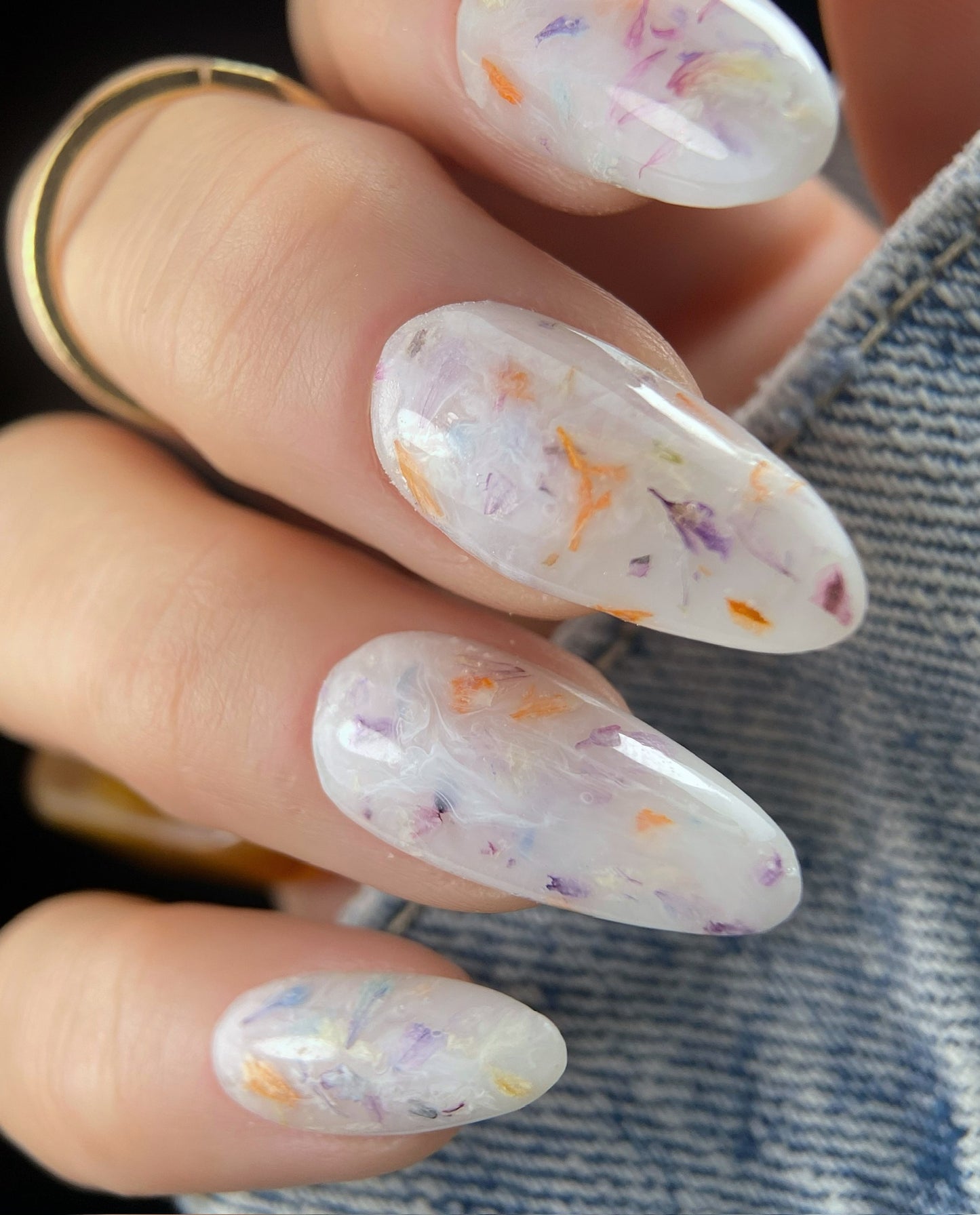 Close-up of a hand with floral nail art on a blurred denim background