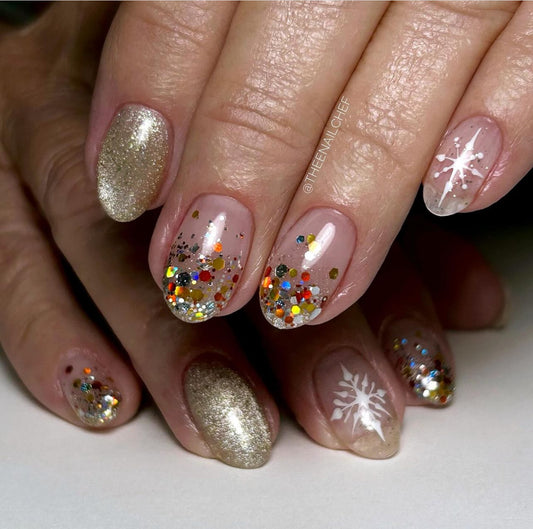 Close-up of hands with decorative nails featuring glitter and snowflake designs.