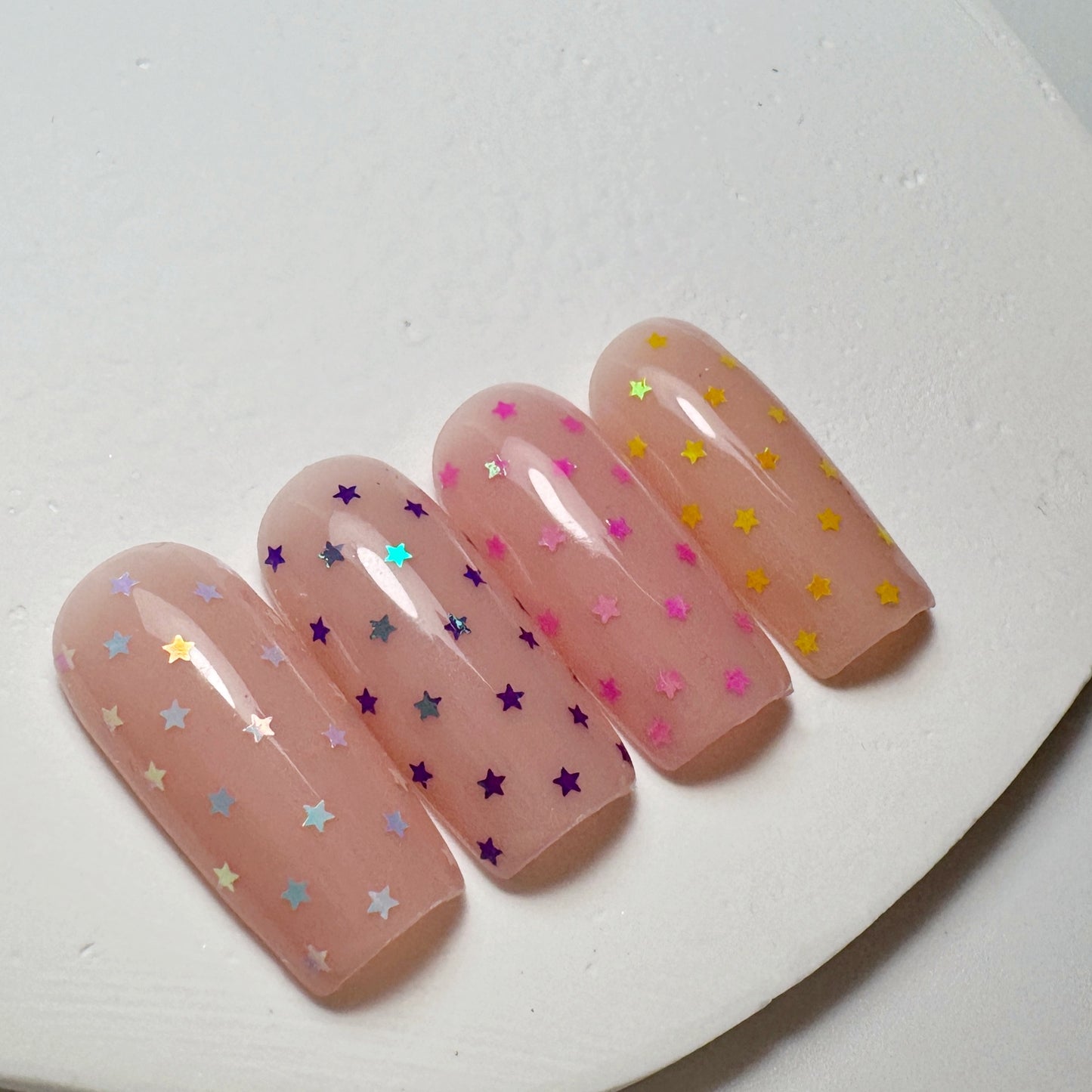 Decorated nail tips on white textured surface.