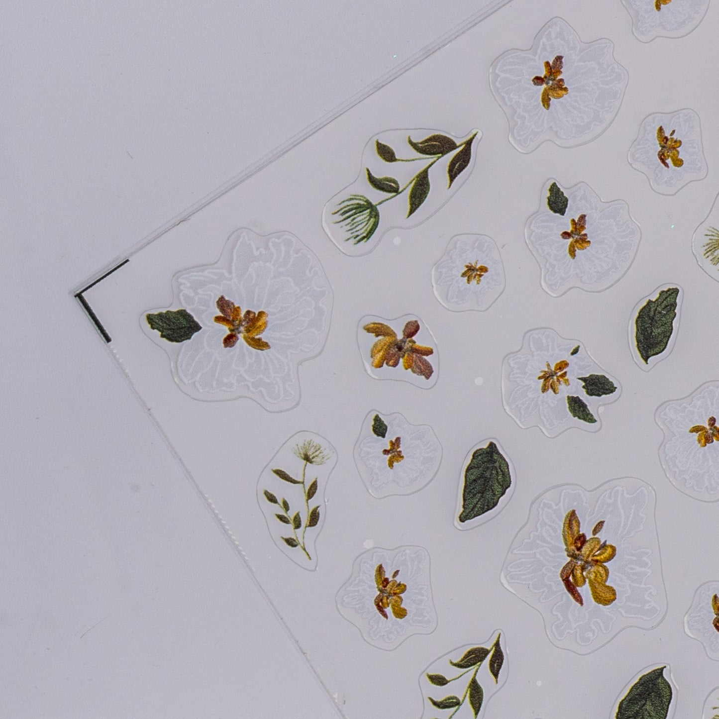 Close up of white floral nail decals on white background.