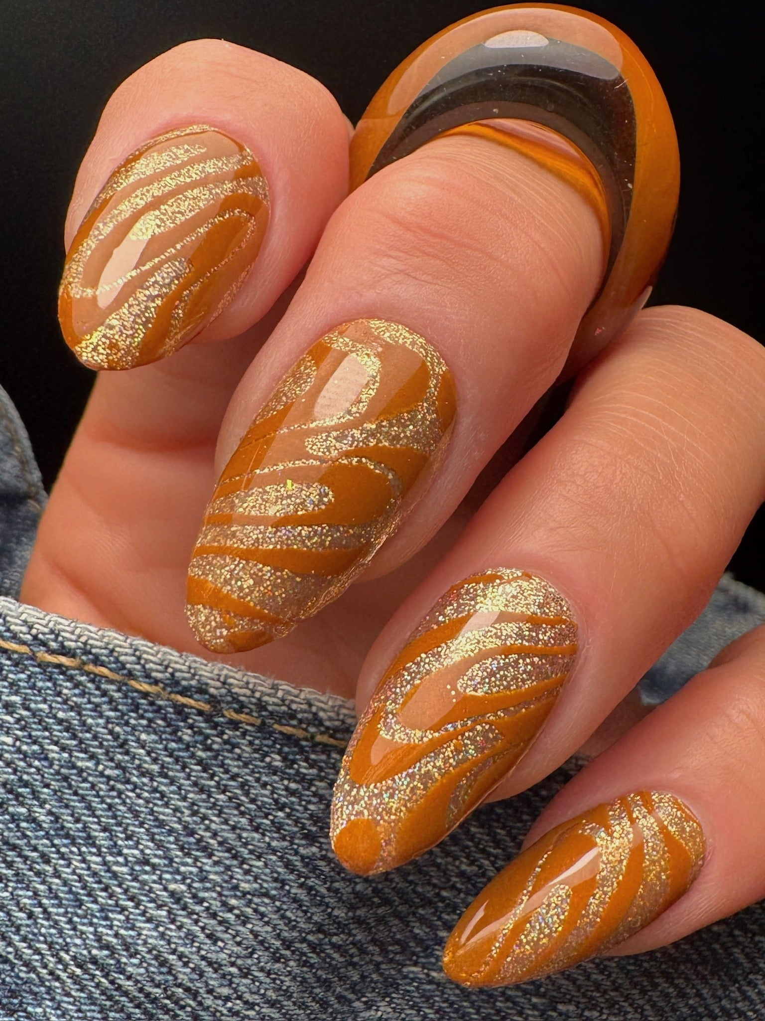 Nails with dark yellow and gold striped design on a dark background