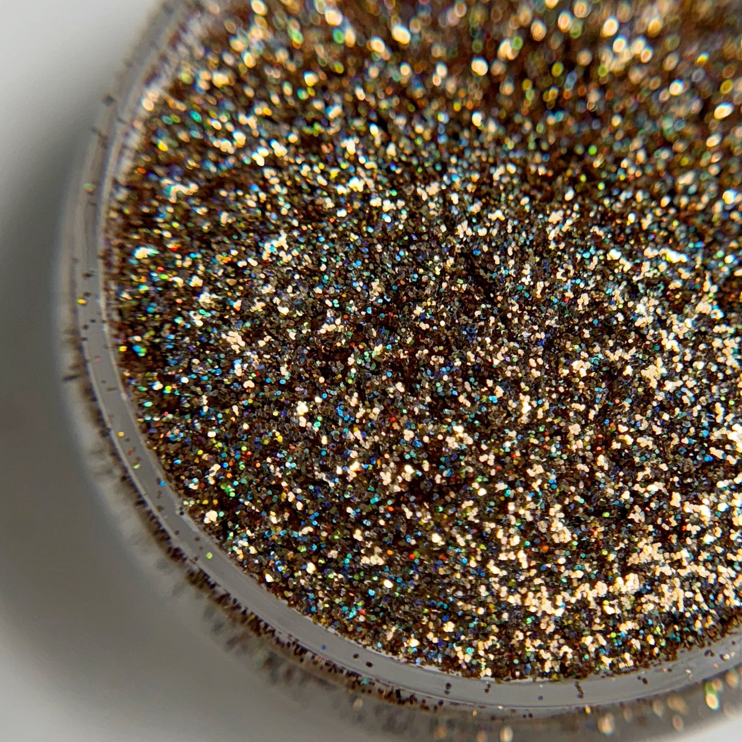 Close up of fine glitter particles in jar on blurred background.