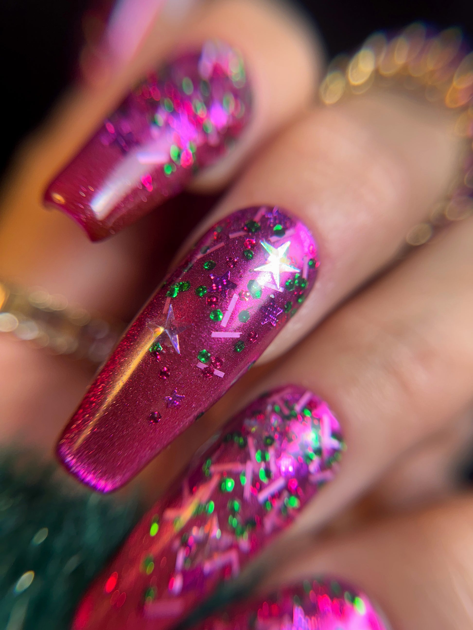 Close-up of a hand with pink glittery nail art on a blurred background