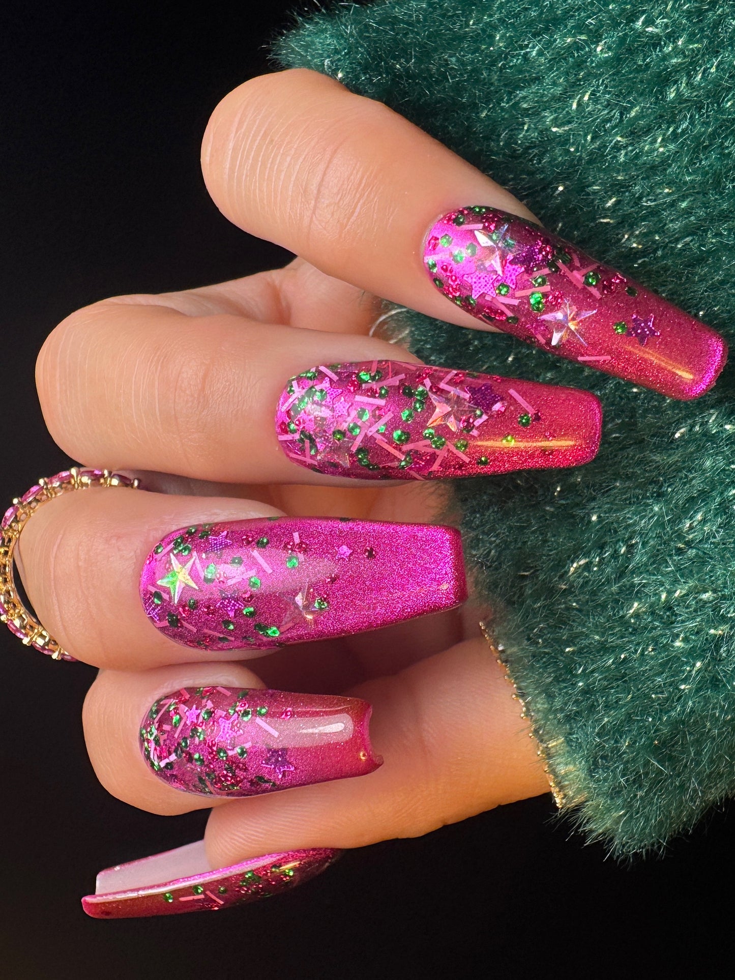 Hand with pink glittery nails against a dark background