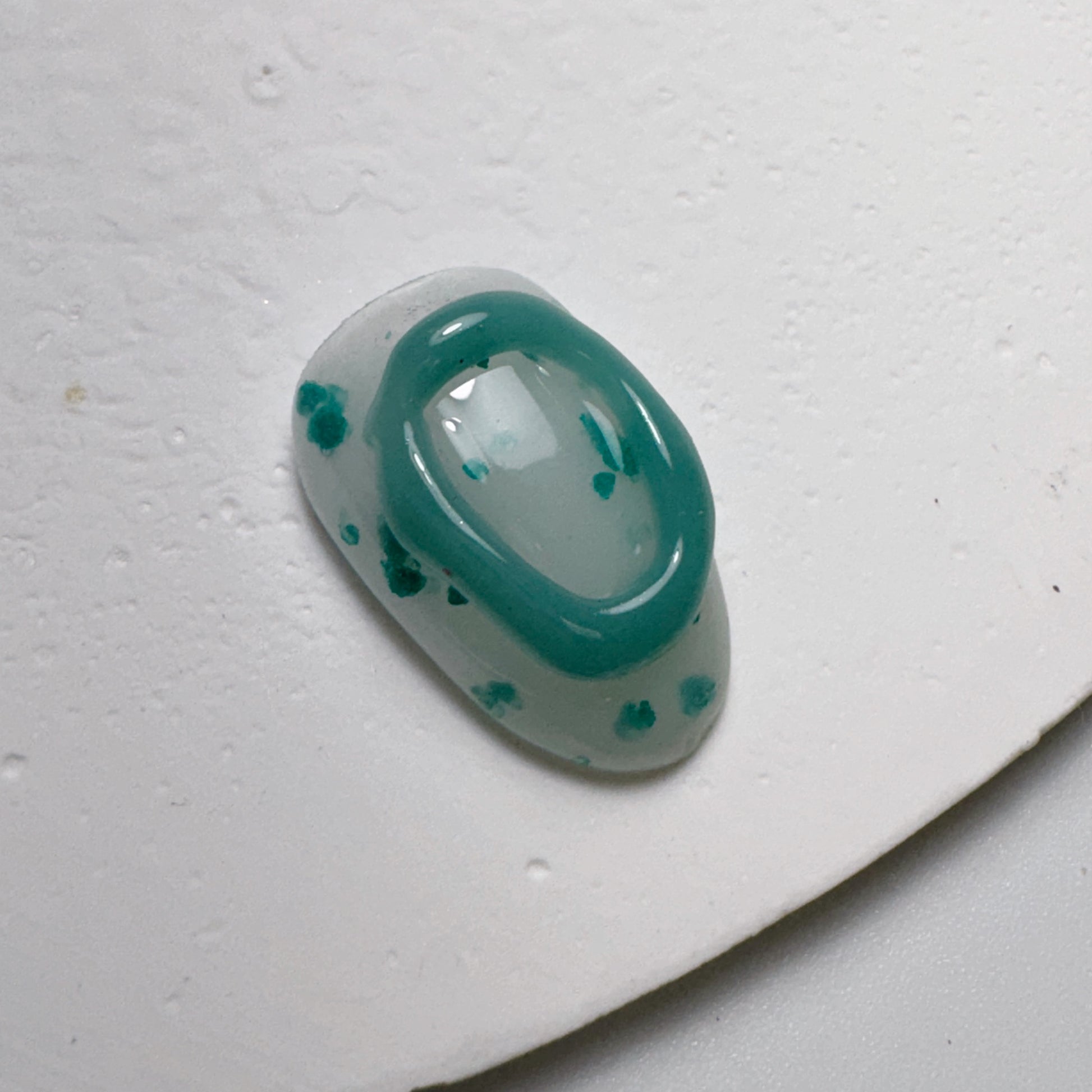Decorated nail tip on textured white surface.