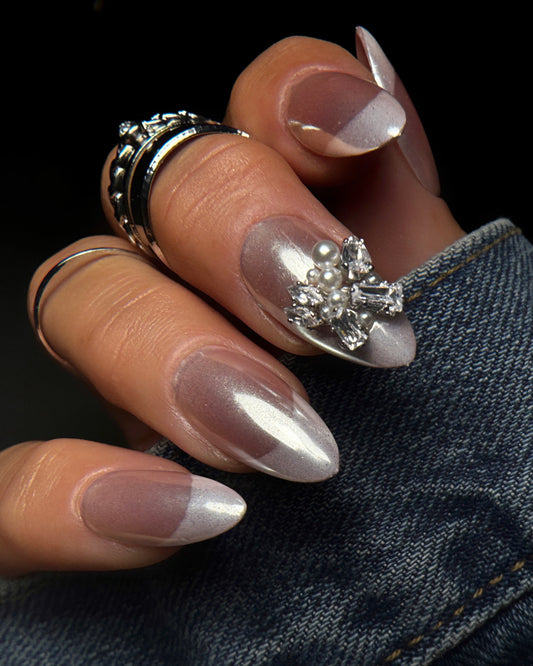 Close-up of a hand with decorative nail art and rings on a dark background