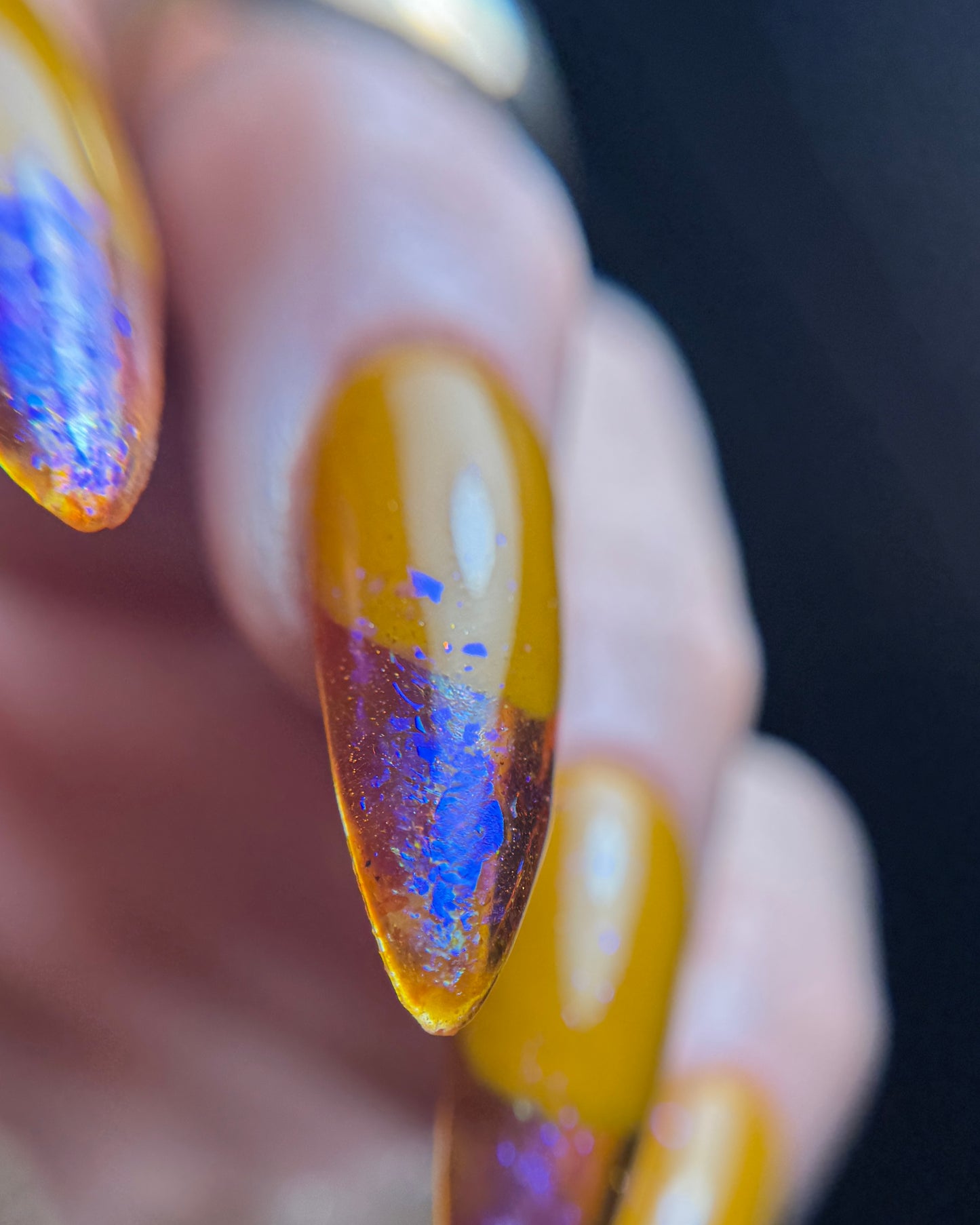 Close-up of a hand with multicolored nail polish on a blurred background