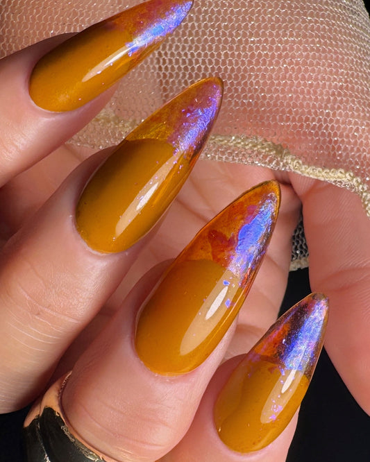 Nail art with dark yellow polish and iridescent purple glitter on a hand