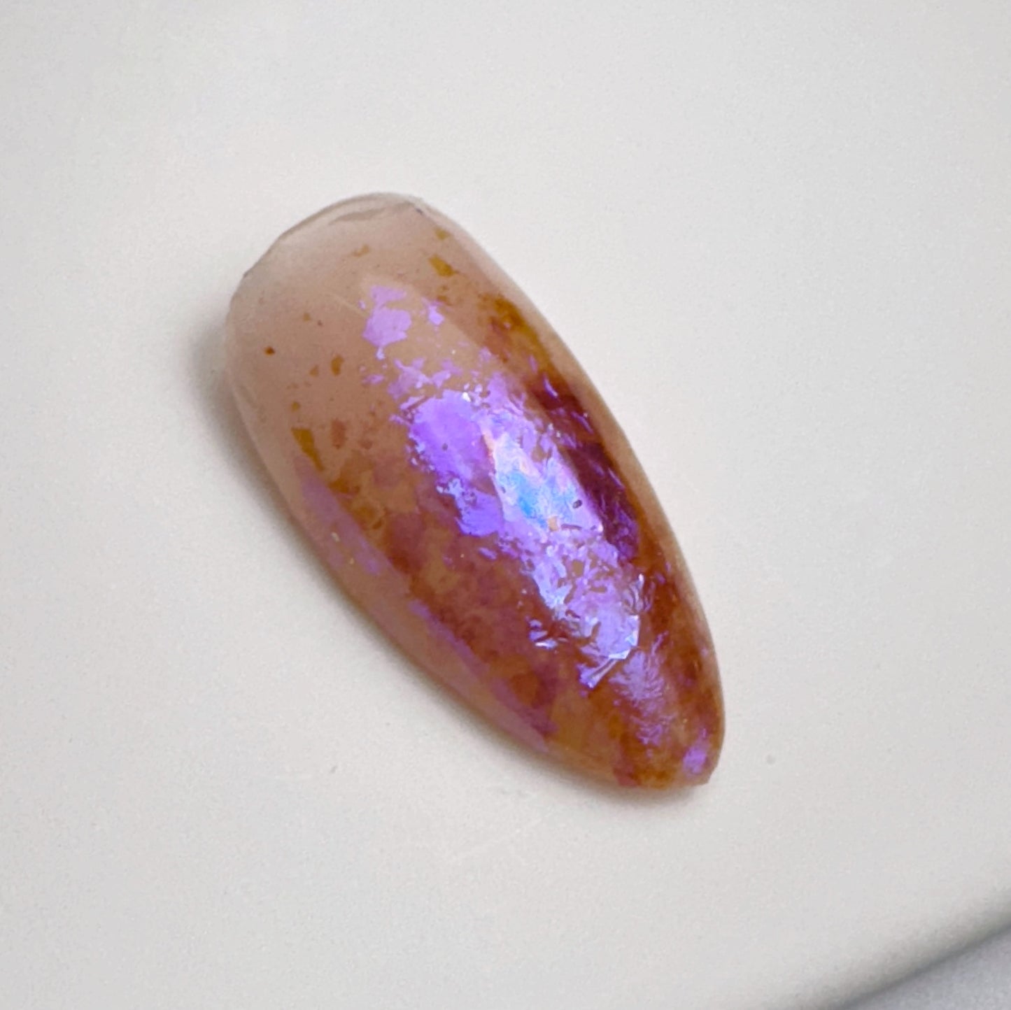 Close up of decorated nail tip on white surface