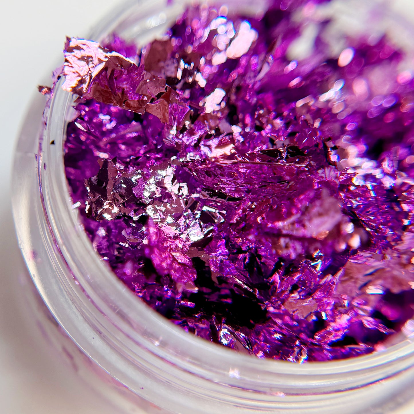 Close-up of nail foil in clear jar on blurred background.
