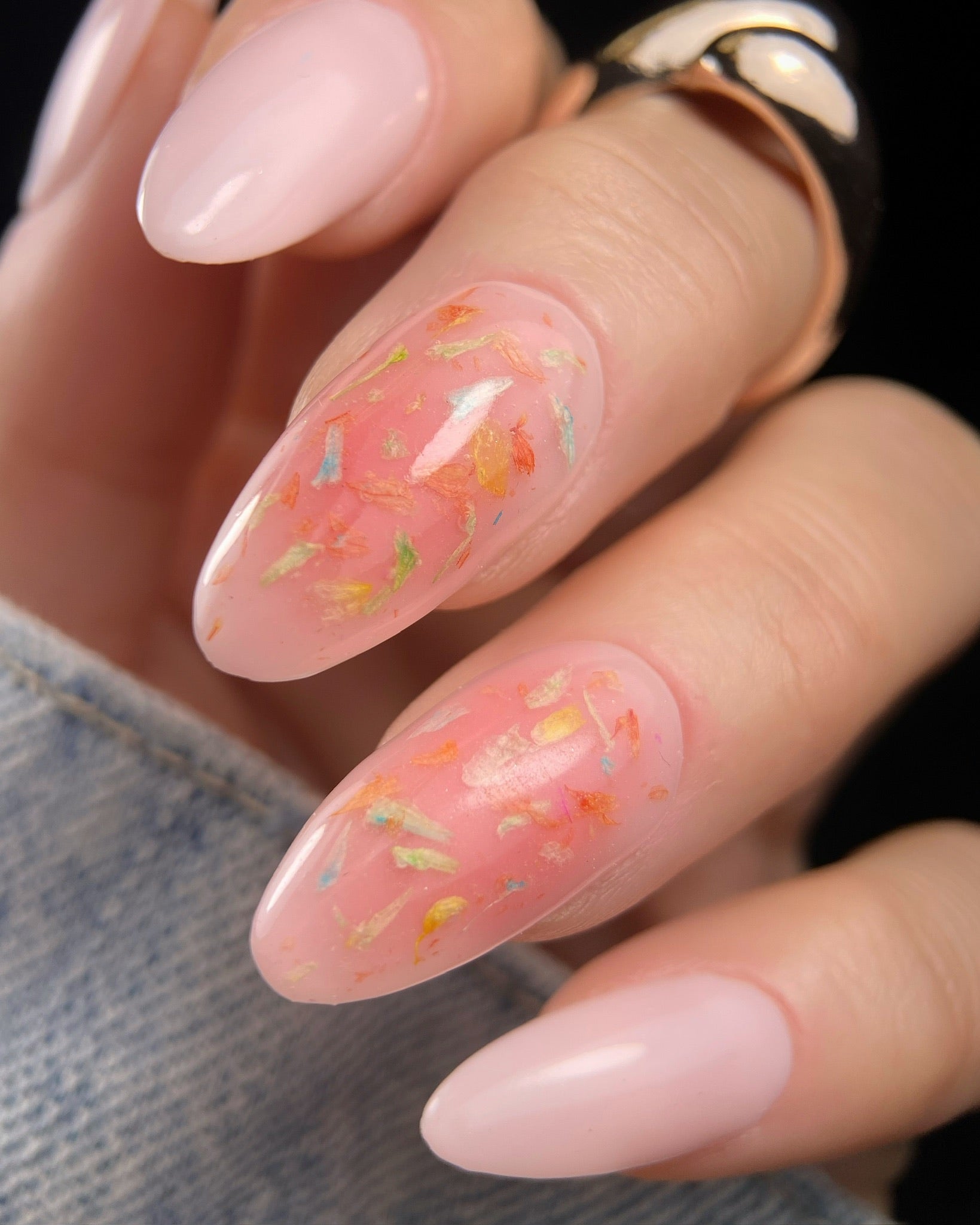 Close-up of a hand with pink nail polish and floral designs.