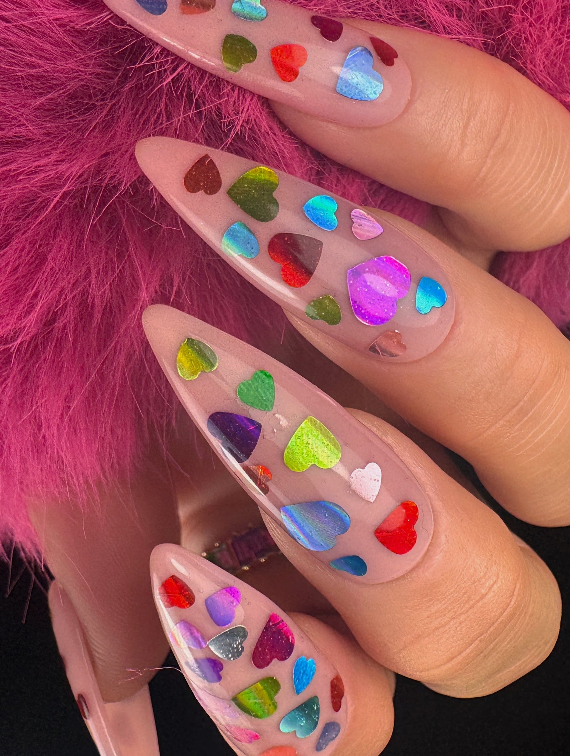 Nails with colorful heart designs on a pink fur background