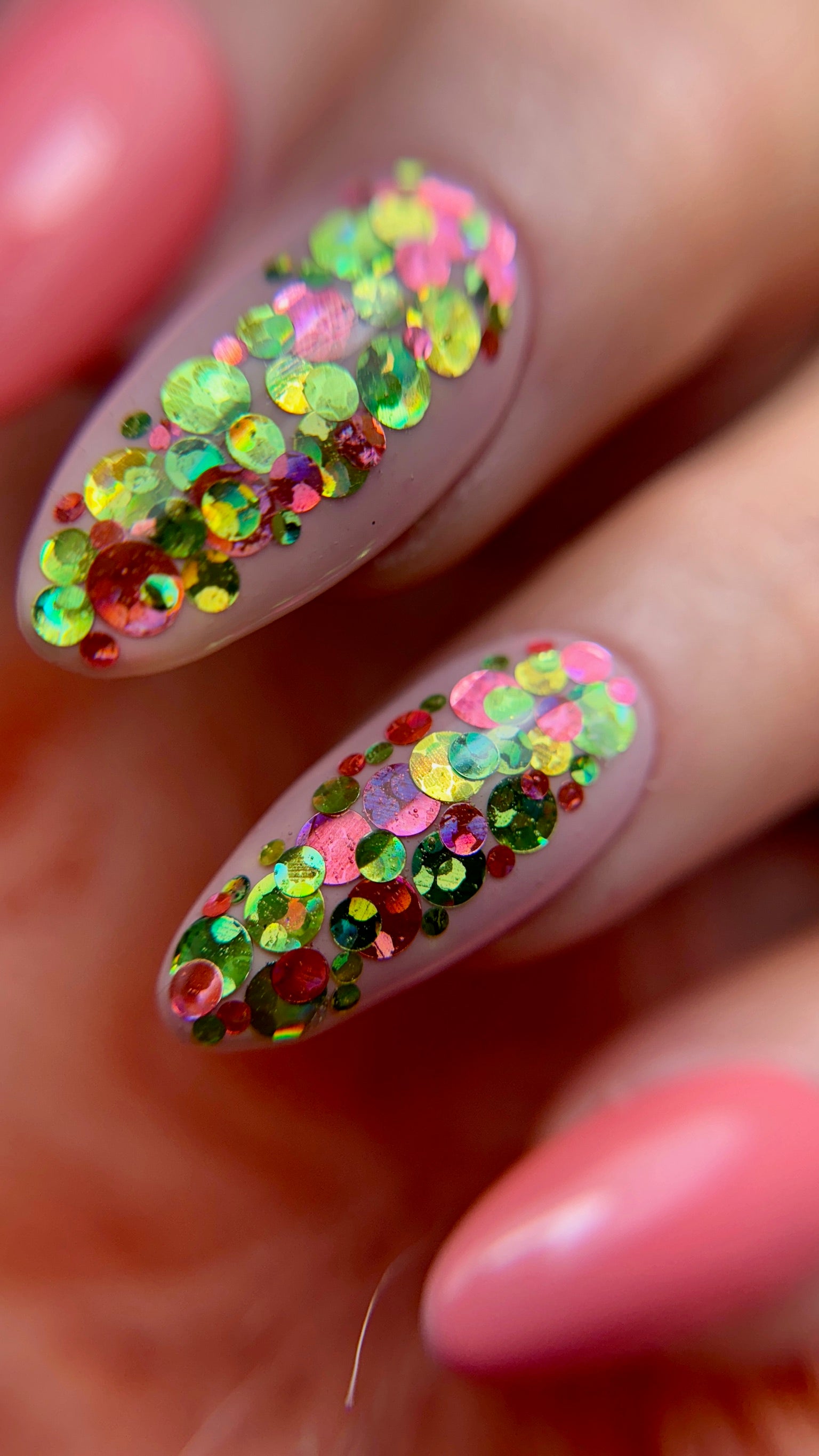 Nails with colorful glitter design on a neutral background