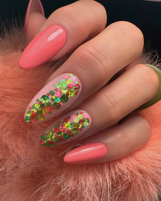 Hand with coral pink nails and glittery design on a fluffy orange surface