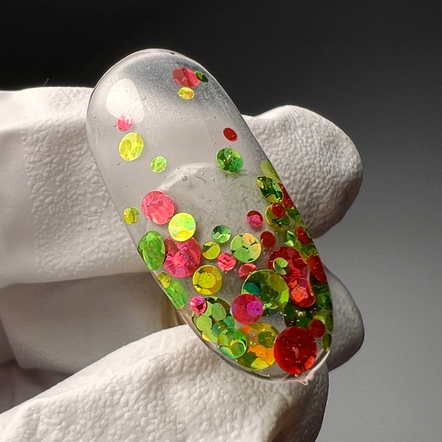 gloved hand holding decorated nail tip