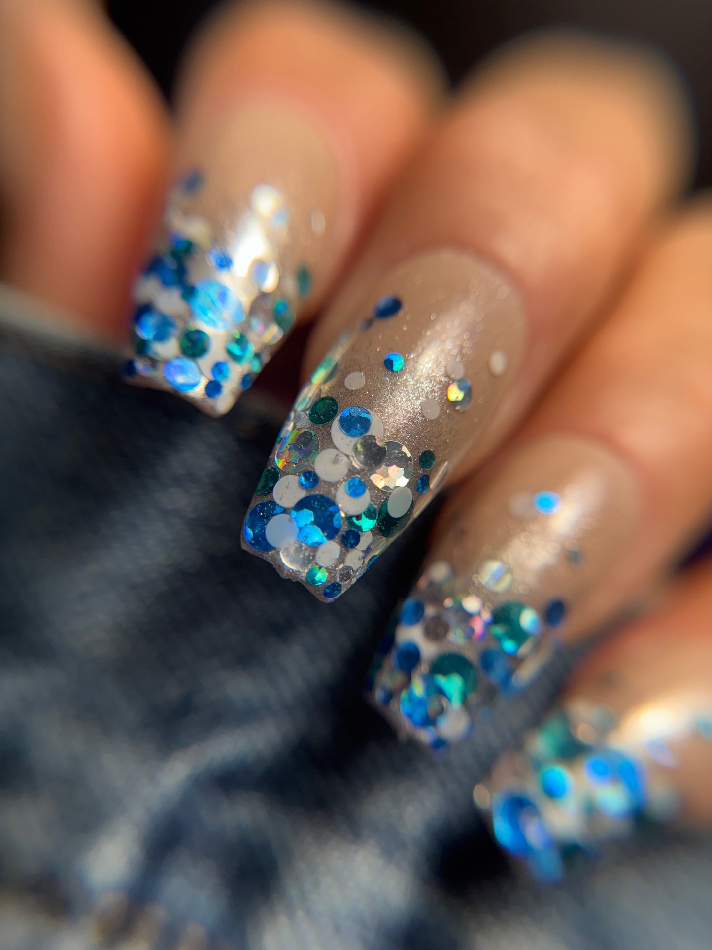Nails with blue and silver glitter on a blurred background