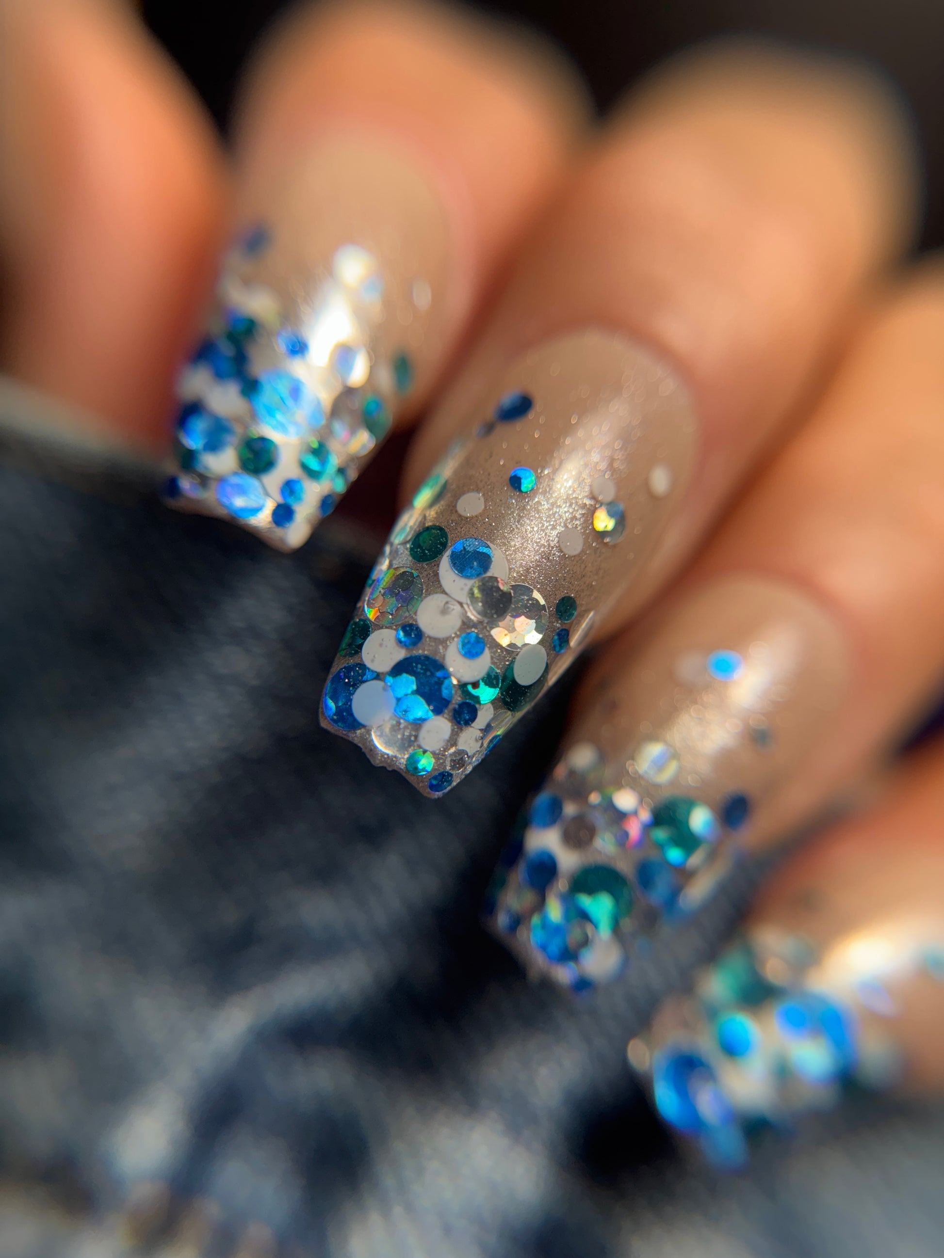 Nails with blue and silver glitter on a blurred background