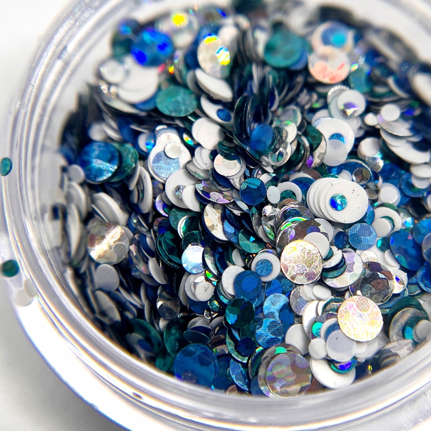 Close-up of round glitter pieces in multiple colors on white background.