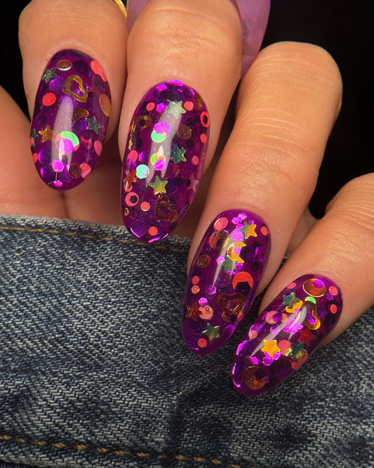 Nails with purple glittery design on a denim background