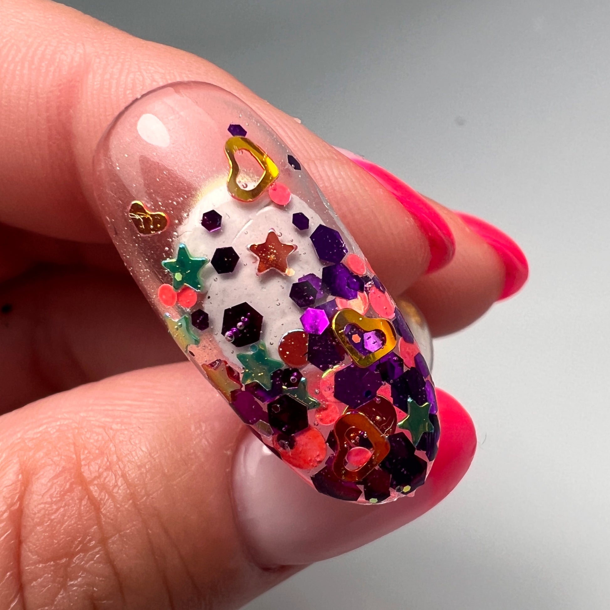 Hand holding decorated nail tip on gray background