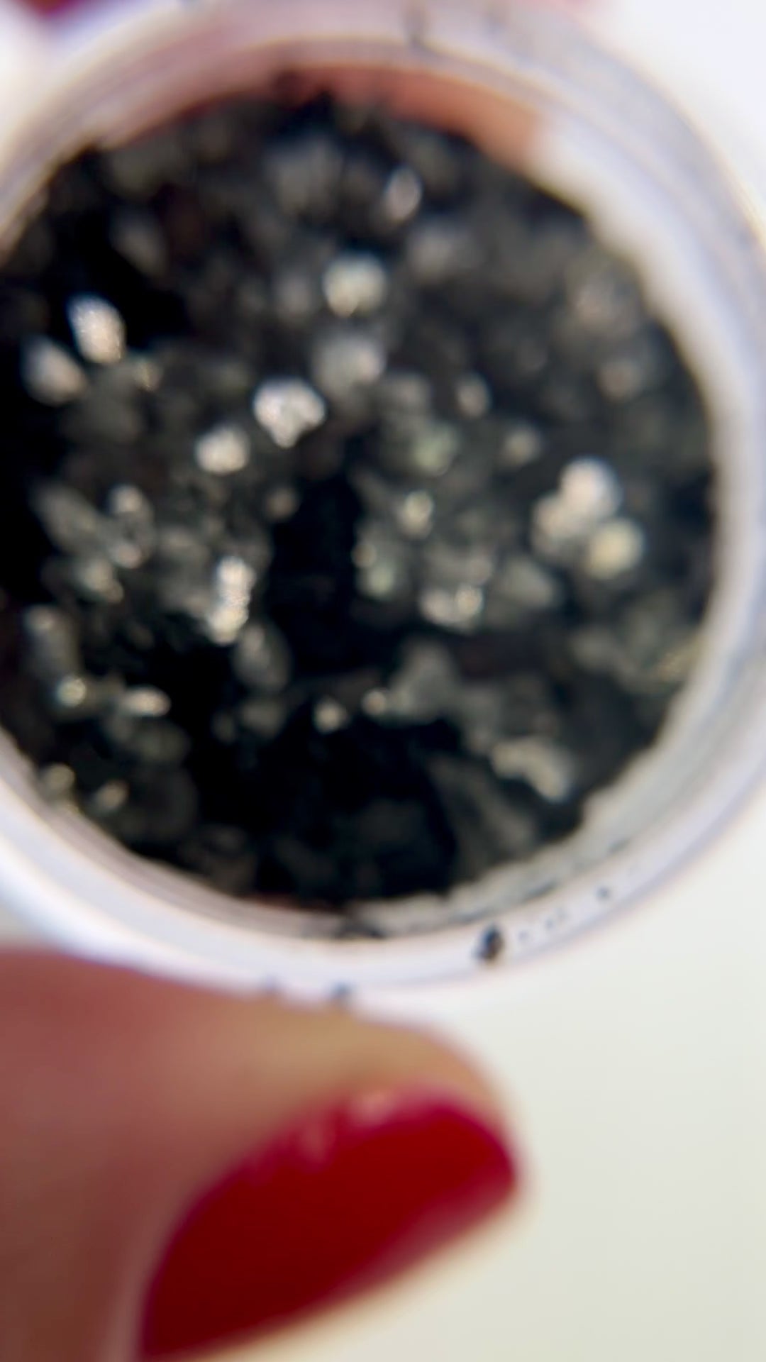 Video of hand holding jar of speckle fragment glitter. 