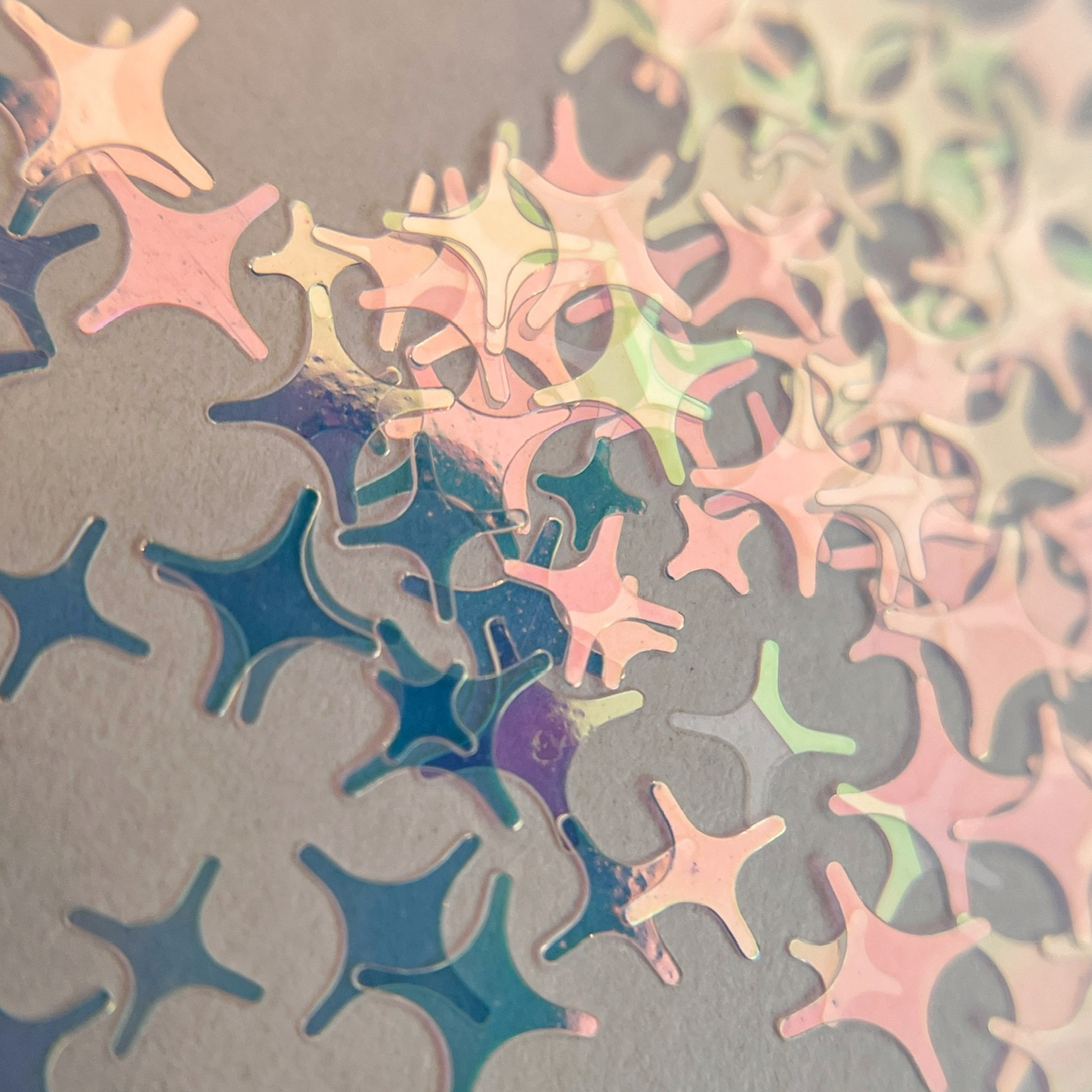 iridescent four point star shaped glitter in a clear jar on a white background. 