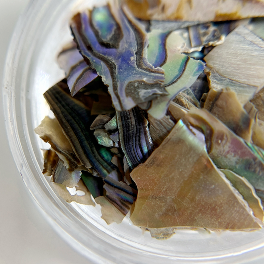 Close up iomage of natural shell flakes in clear jar on white background. 