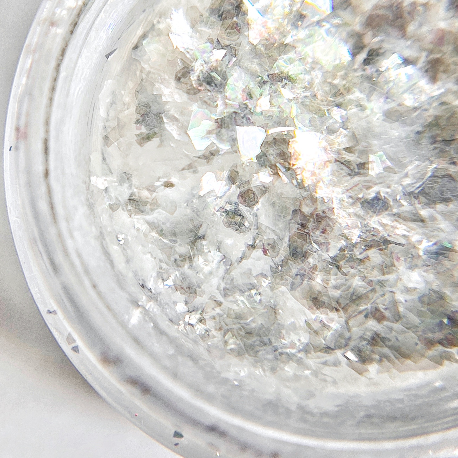 Sheer white flakes in clear jar on white background.