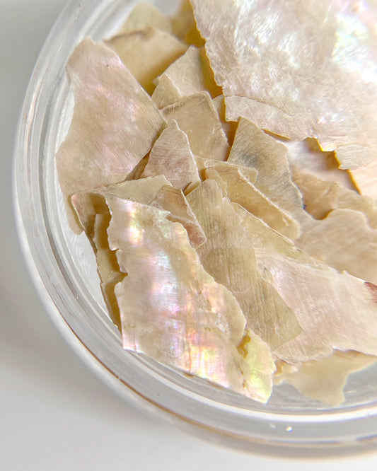 Close up iomage of natural shell flakes in clear jar on white background. 
