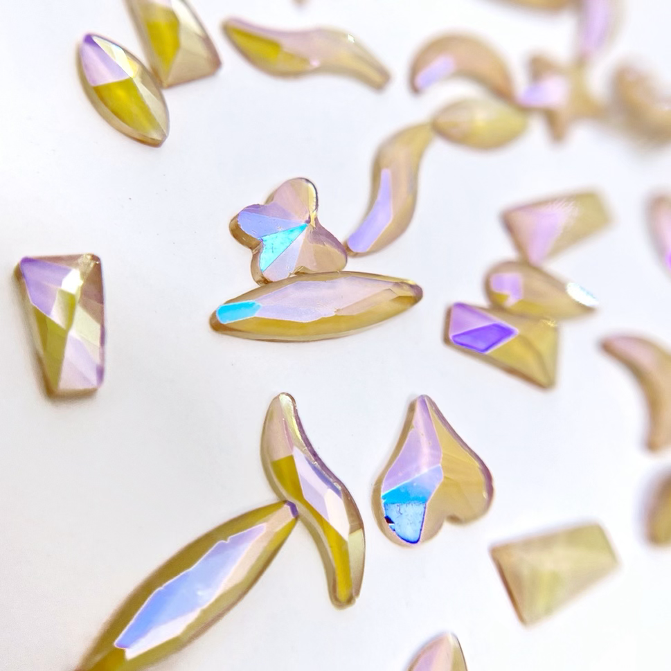 Multi shape iridescrnt rhinestones scattered on a white background. 