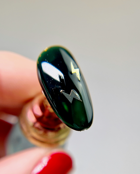 Hand holding decorated nail tip. 