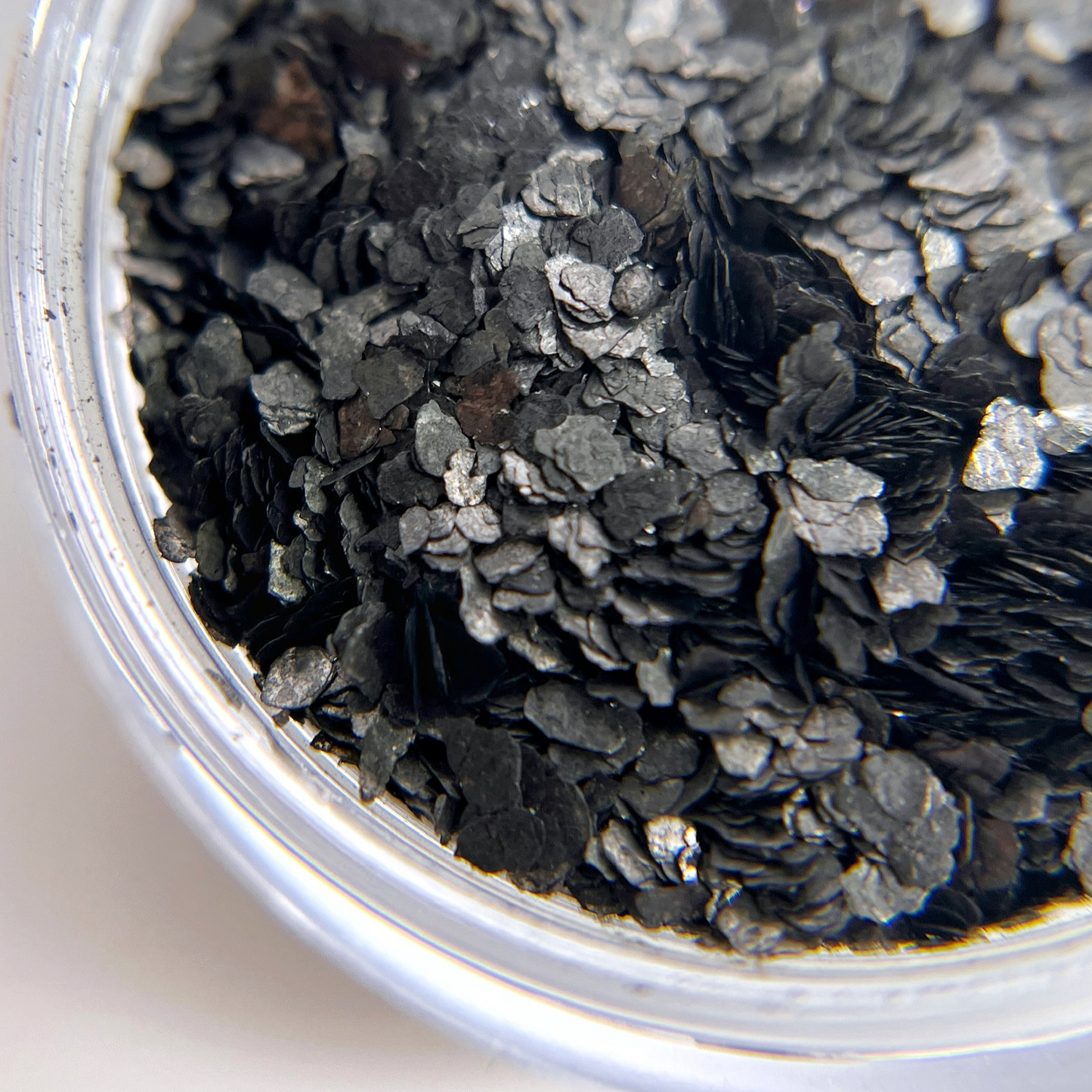 Close up of black speckle fragment glitter in jar. 