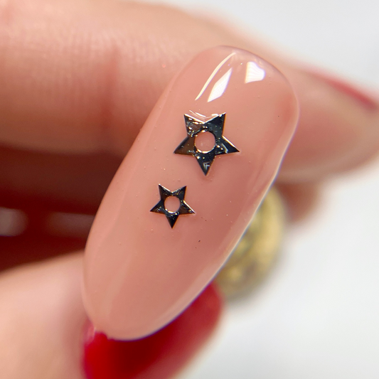 Hand holding decorated nail tip. 