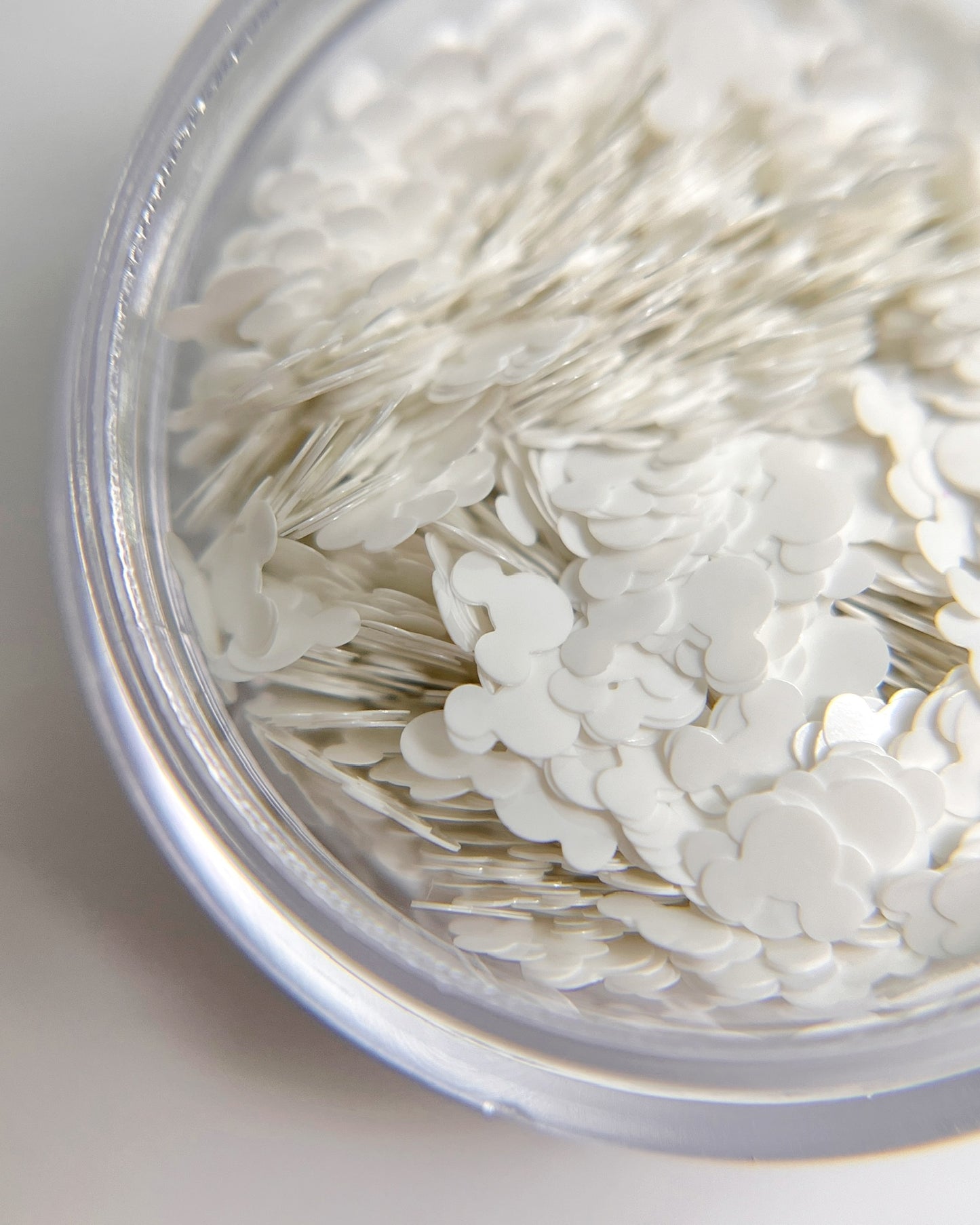 Close up of white mouse-shaped glitter in transparent jar on blurred background